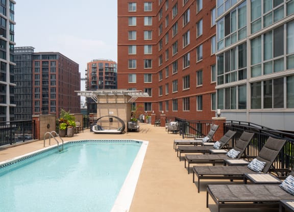 a swimming pool with lounge chairs in front of a building