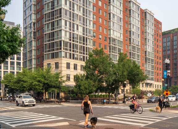 a woman crossing a street in front of an apartment building