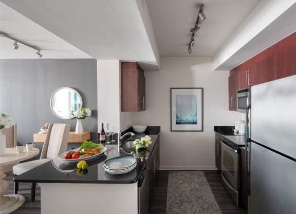 kitchen and living room of an apartment with stainless steel appliances and a black counter top