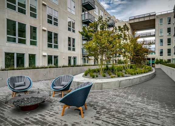 A patio with blue chairs and a fire pit.