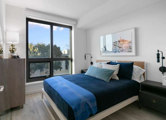 A bedroom with a large bed and a painting on the wall.