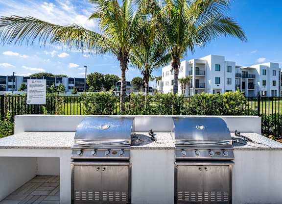 Two built-in BBQ grills in a white outdoor kitchen.
