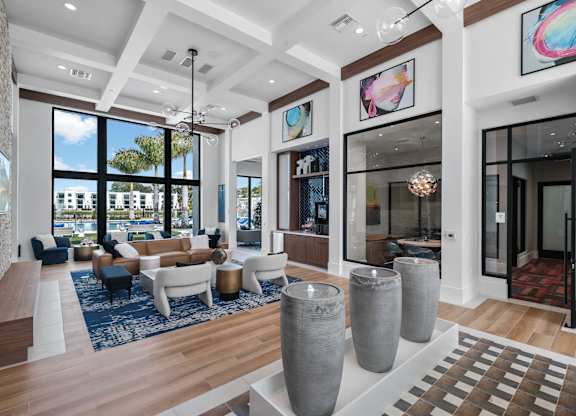 A spacious living room with a large window, a sofa set, and a rug.