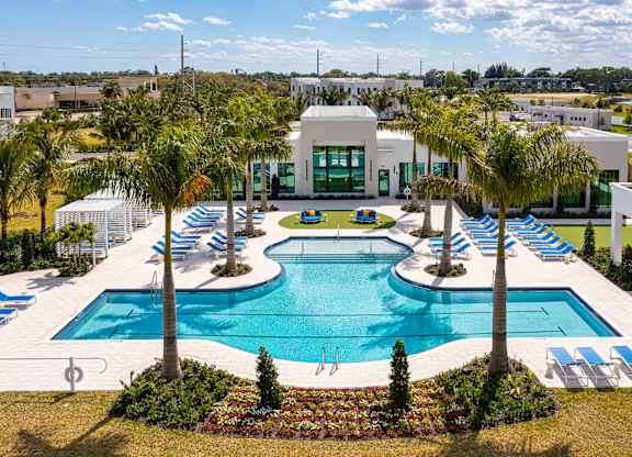 A large swimming pool surrounded by palm trees and lounge chairs.