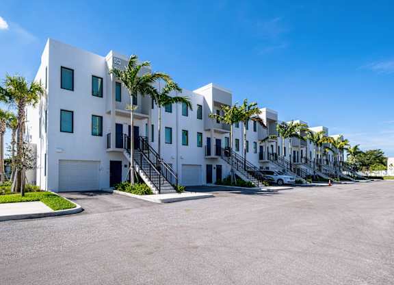 A white building with palm trees in front.