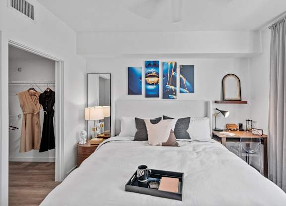 A bedroom with a large bed, a desk with a chair, and a painting on the wall.
