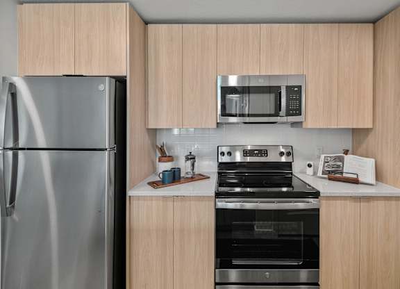A kitchen with a stainless steel refrigerator, a microwave, and a stove top oven.