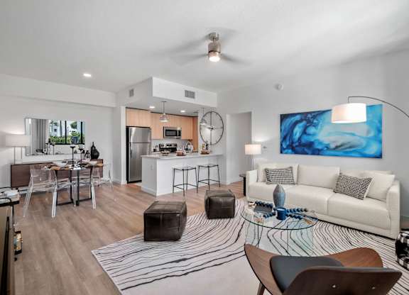 A modern living room with a white couch and a large painting on the wall.