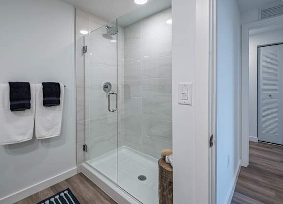 A bathroom with a glass shower stall and towel racks.