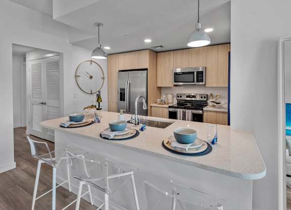 A modern kitchen with a white island and chairs.