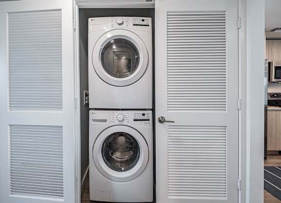 A white washing machine is in a cabinet with a door open.