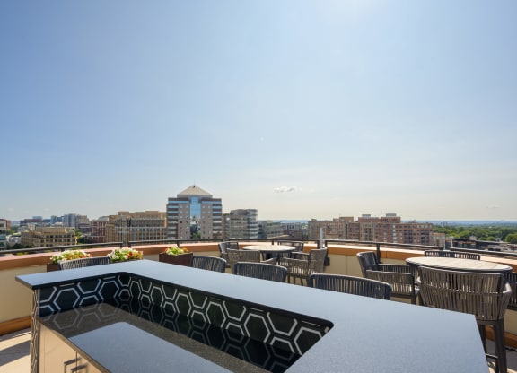 a rooftop patio with tables and chairs and a view of the city