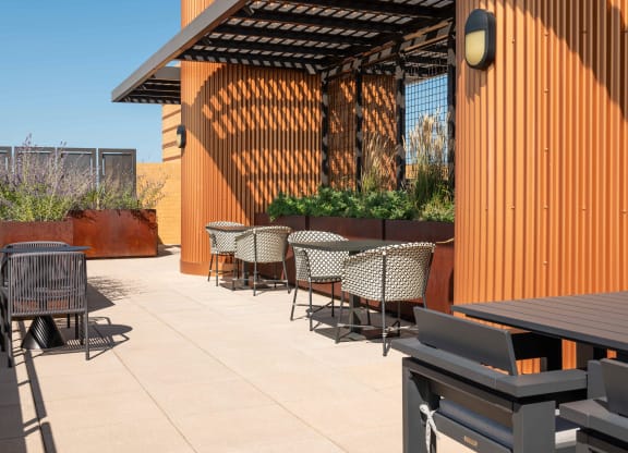 a patio with tables and chairs and a wood fence