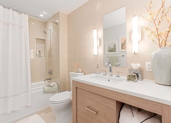 a bathroom with beige tiles and a white shower curtain