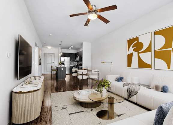 Light-filled living room at 7001 Arlington at Bethesda in Bethesda, MD, with sectional seating, a wall-mounted TV, wood-style flooring, a dining area, and an open kitchen.
