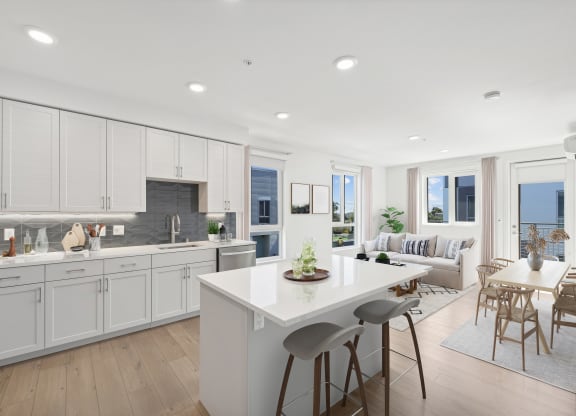 a white kitchen with a white island and a living room