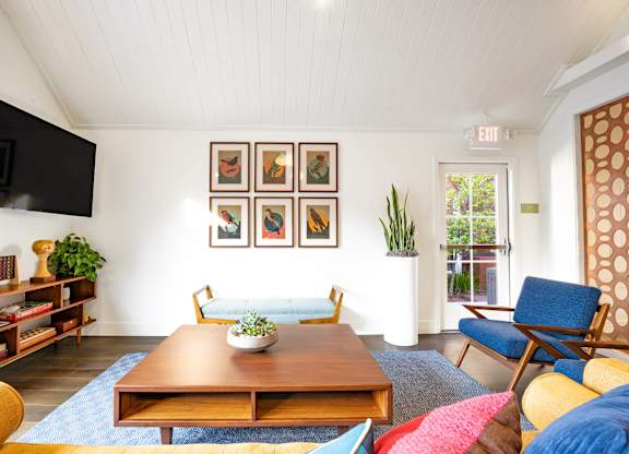 A living room with a blue rug and a wooden coffee table.
