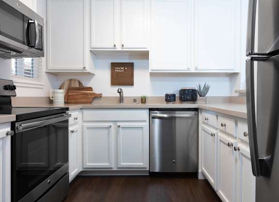 A kitchen with white cabinets and a wooden cutting board.