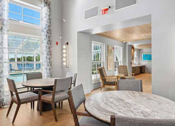 Resident lounge at Marlin Cove Apartments with dining tables, modern seating, and pool views.