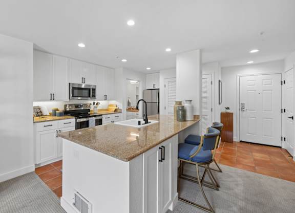 Modern kitchen at Marlin Cove Apartments with granite island, white cabinetry, and stainless steel appliances.
