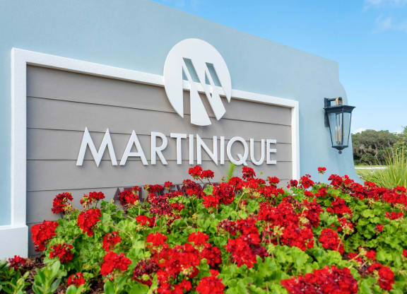 a gray building with a sign that says martinique and red flowers in front of it
