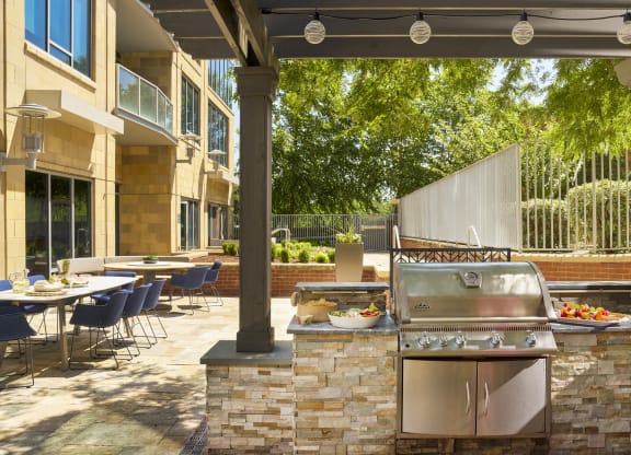 a patio with a grill and tables with chairs