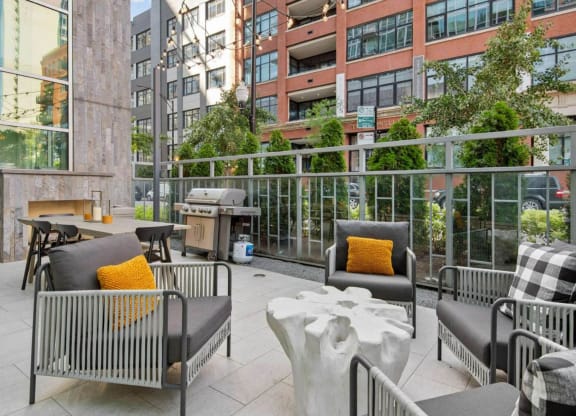 a patio with chairs and tables and a grill on the side of a building