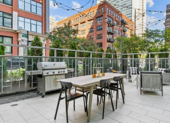 a patio with a table and chairs and a grill