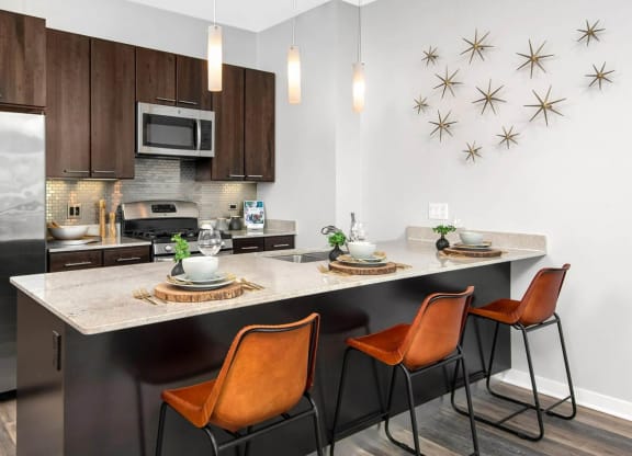 a kitchen with a large island with three orange chairs in front of it