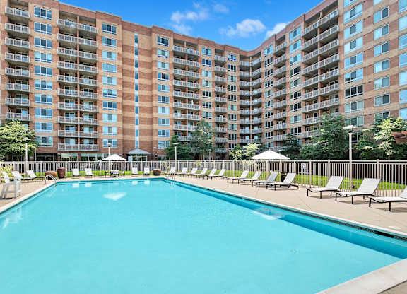 A large swimming pool in front of a multi-story apartment building.