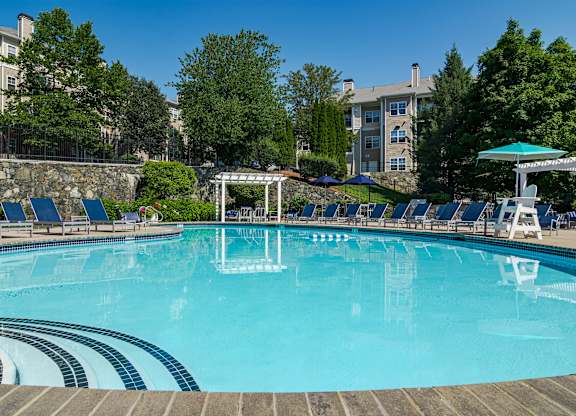 A large swimming pool with a stone wall and sun loungers.