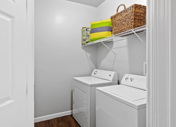 a laundry room with a washer and dryer and a basket on a shelf