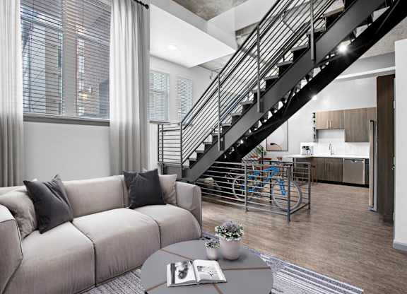 Elegant living room with contemporary furniture and a staircase behind it.