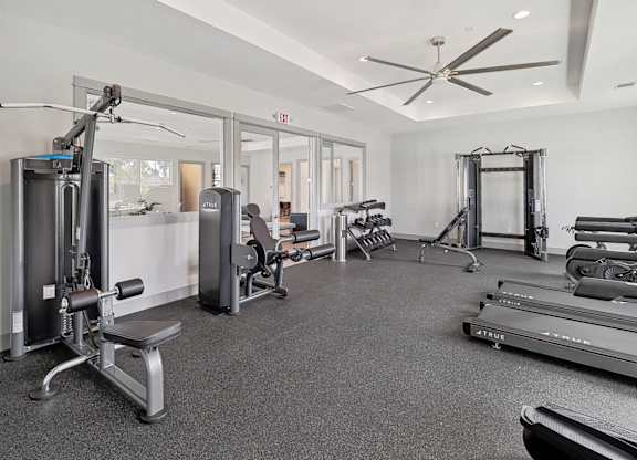 A spacious gym with a variety of equipment including treadmills, weights, and a bench press.