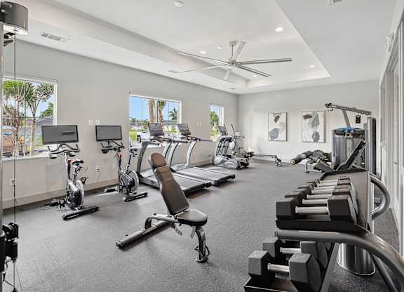 A spacious gym with a variety of equipment including treadmills, stationary bikes, and weight machines.