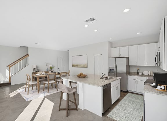 a kitchen and living room with a staircase in the background