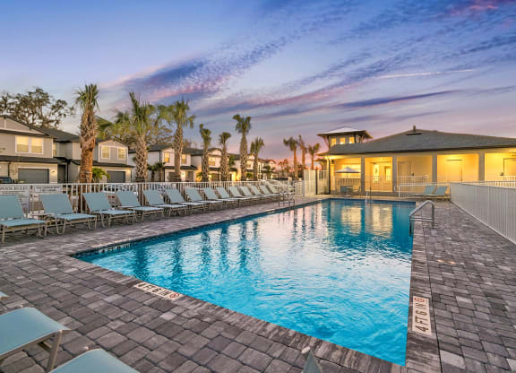 a swimming pool with chaise lounge chairs and a building in the background
