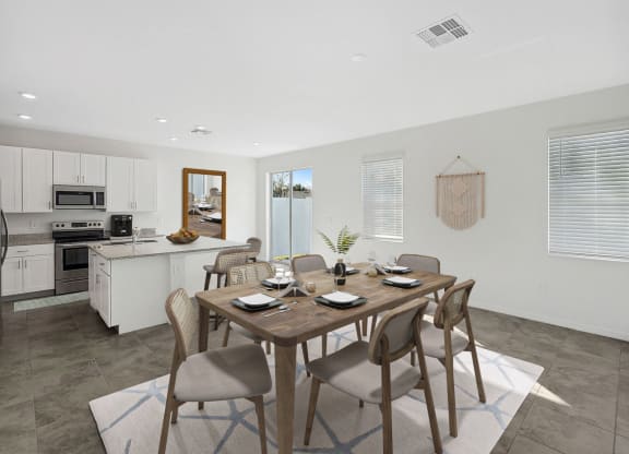 a dining area with a table and chairs and a kitchen in the background