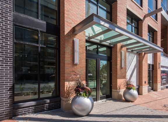 A modern building with a glass entrance and two large planters in front.