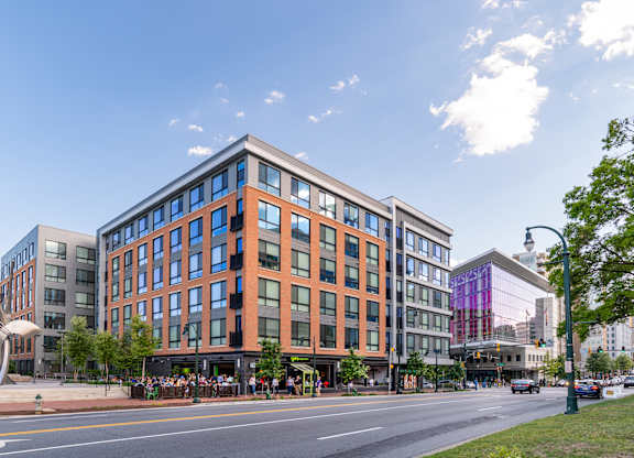 A modern building with a glass facade is situated on a street corner.