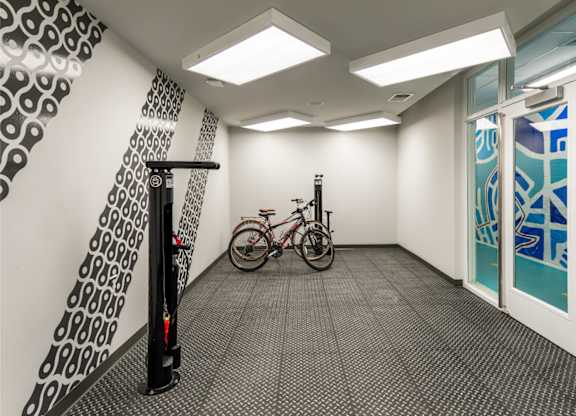 A bicycle is parked in a hallway with a black and white patterned wall and a glass door.