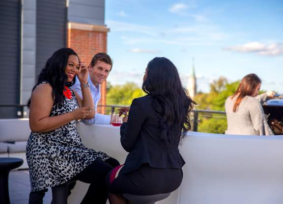 Three people are sitting on a white couch outside.