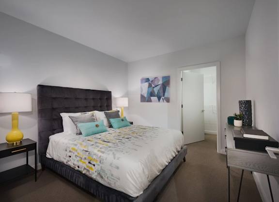 A bedroom with a large bed and a nightstand with a lamp.
