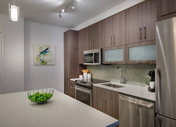 A modern kitchen with a stainless steel refrigerator, microwave, and oven.