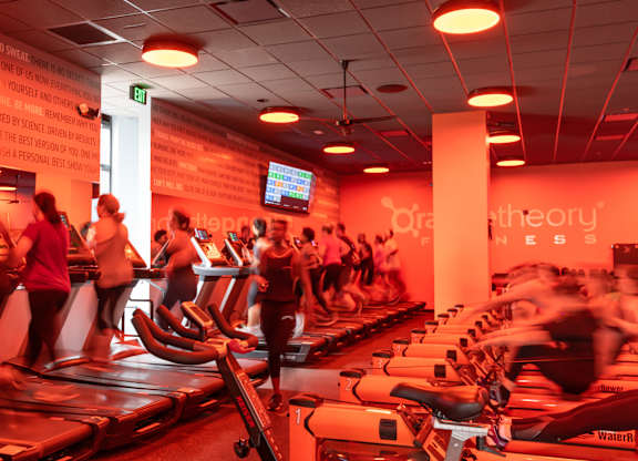 A gym with people exercising and treadmills.