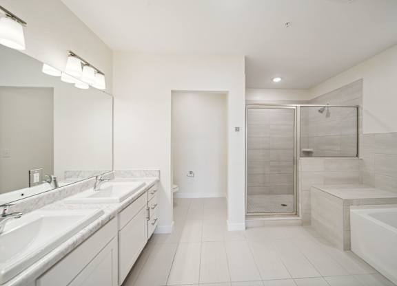 A white bathroom with a large mirror and a walk-in shower.