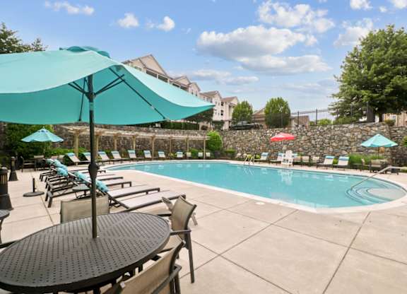 A pool with a table and chairs and umbrellas.