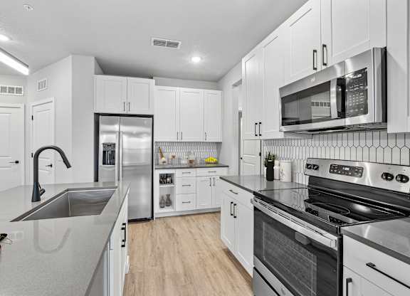 A modern kitchen with stainless steel appliances and white cabinets.