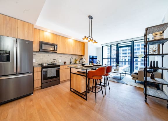 a kitchen with stainless steel appliances and a bar with chairs
