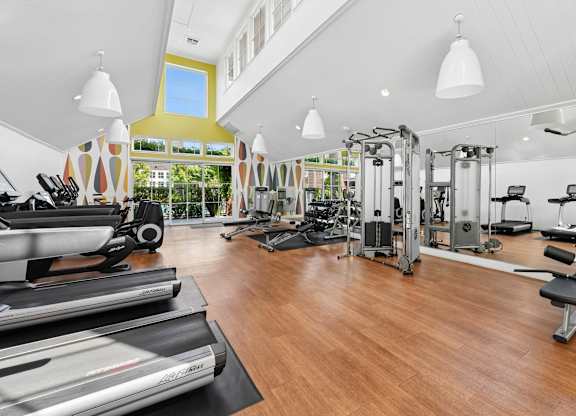 Spacious fitness center at Grove Apartments featuring cardio machines, weight equipment, and mirrored walls.